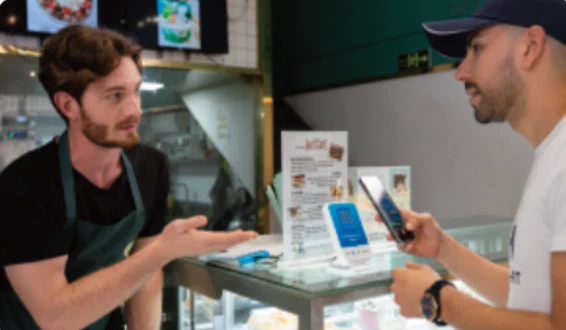Merchant and customer at a counter with a sound box